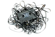 Una musicassetta Maxell con il nastro srotolato e ingarbugliato tutto intorno