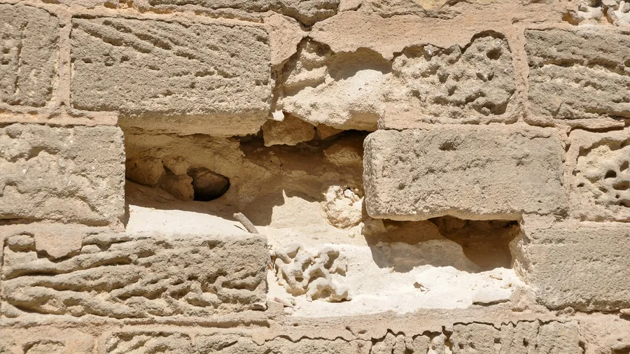 Muro di blocchi di arenaria con una cavità scavata dall'erosione: dignità organizzativa e adeguati assetti si consumano dall'interno